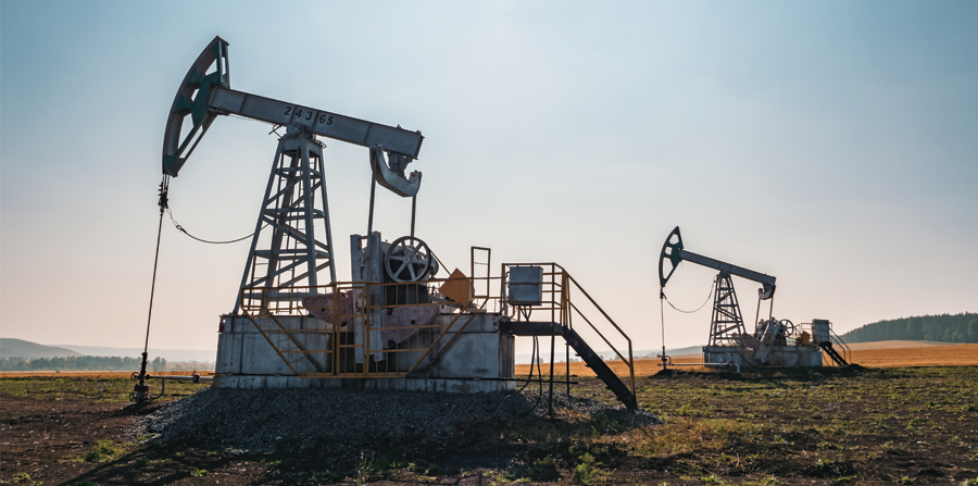 oil pumps operate in a vast field under a clear blue sky at midday in rural area