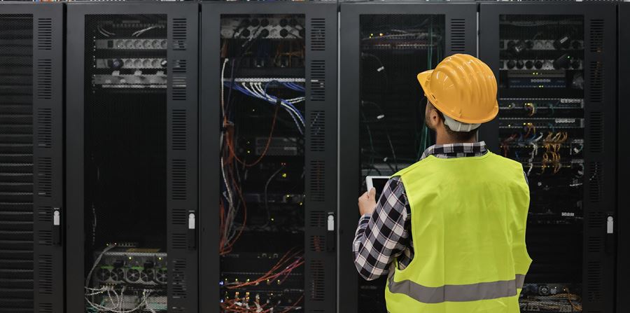technician man working with tablet inside big data center room full of rack servers