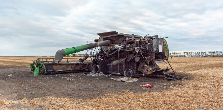 backside view of burnt combine harvester on grain field